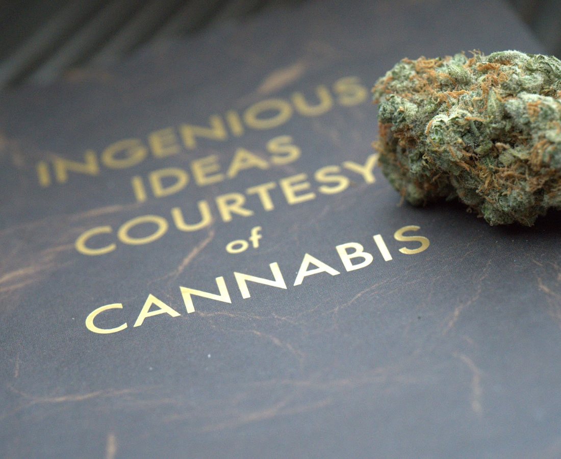 A book cover reading Ingenious Ideas Courtesy of Cannabis beside a cured bud